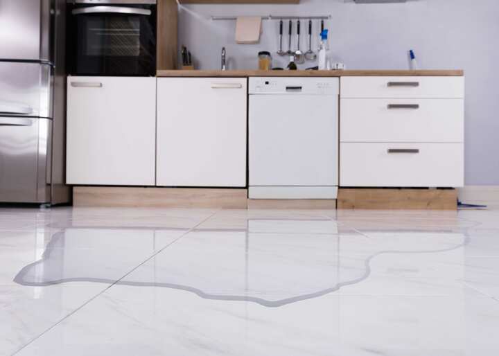 A kitchen with leaking water covering the floor in need of water damage cleanup in Hamden, CT